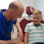 Wir zeigen ihnen, ihre Zähne zu wertschätzen, richtig zu pflegen und wie wichtig die regelmäßige Vorsorge ist. Kind auf dem Zahnarztstuhl